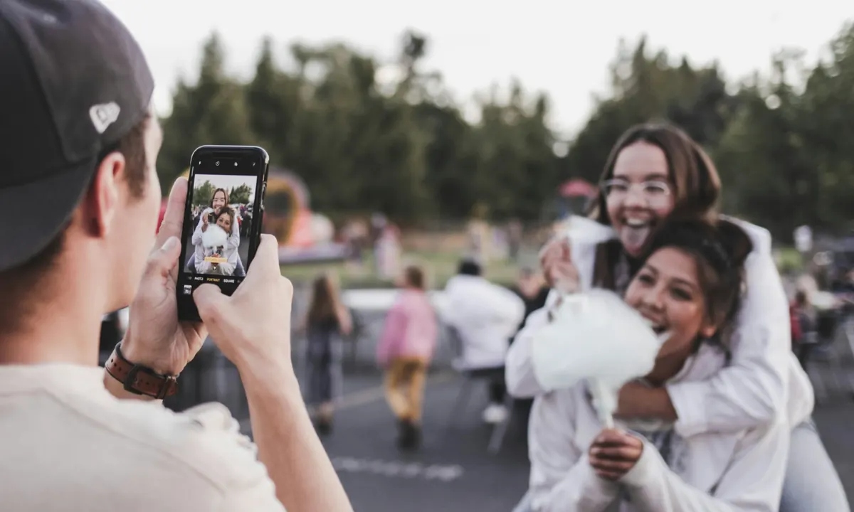 A man taking a phone photo of two laughing friends