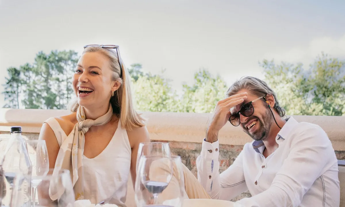 A couple laughing over lunch with wine glasses