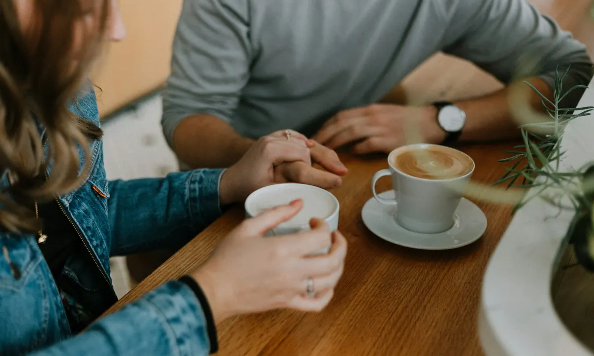 Two people talking over coffee at a wooden table